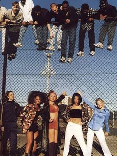 several people standing on top of a chain link fence