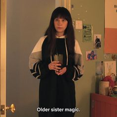 a woman standing in front of a door holding a cup and looking at the camera