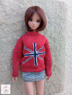 a doll is wearing a red sweater with the british flag on it