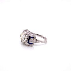 a diamond and blue stone ring on a white surface with the center stone surrounded by diamonds