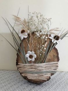 a wooden bowl with flowers in it sitting on a table next to a white wall