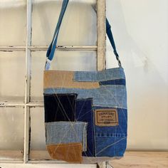 a bag made out of old jeans hanging on a window sill in front of a white brick wall