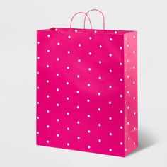 a pink shopping bag with white polka dots on the front and bottom, against a blue background