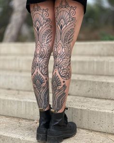 a woman with tattoos on her legs and leggings is standing on some steps