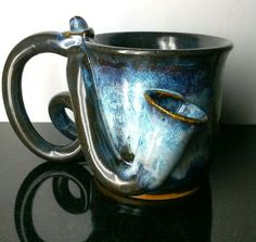 a blue and white coffee cup sitting on top of a black table next to a wall