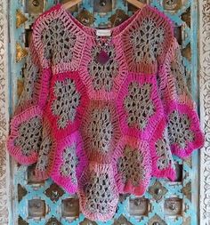 a crocheted sweater hanging on a wooden hanger