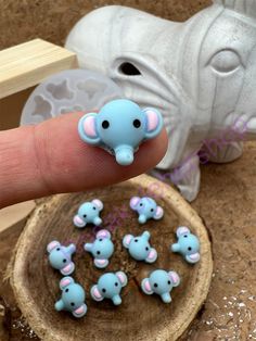 a tiny elephant figurine sitting on top of a piece of wood next to small elephants