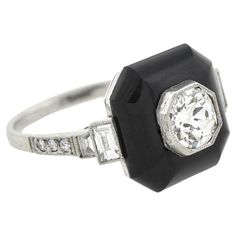 A striking ring from the Art Deco (ca1920s) era! Crafted in platinum, this ring adorns an Old Mine Cushion Cut diamond within an octagonal milgrained bezel. The diamond, weighing approximately 0.75ctw in beautiful H color and VS2 clarity, is raised above a deep black onyx stone. The shoulders are adorned on each side by two baguette diamonds and three Single Cut diamonds, bringing the ring's total weight to 1ctw atop an attractive airline. This piece would be a wonderful addition to any Art Deco Art Deco Octagon Ring With Center Stone, Art Deco Octagon Ring With Bezel Setting, Art Deco Octagon Bezel Set Ring, Art Deco Octagon Ring With Prong Setting, Gia Certified Art Deco Octagon Ring, Art Deco Platinum Octagon Ring, Art Deco Octagon Platinum Ring, Cushion Cut Diamond, Baguette Diamonds