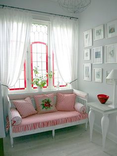 a red and white striped couch in front of a window with pictures on the wall