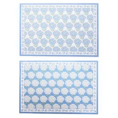 two blue and white placemats with flower designs on the edges, one in front of