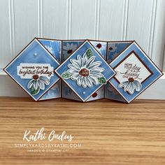 three handmade greeting cards with daisies on them, sitting on a table in front of a door