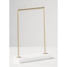 a white and gold display stand with two metal bars on it's sides, in front of a white background