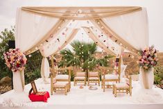 an outdoor wedding setup with white drapes and pink flowers