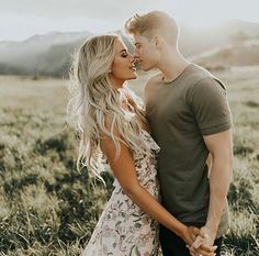 a man and woman are standing in the grass