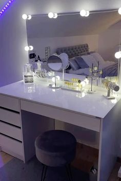 a white vanity with lights on it and a stool in front of the mirror that is lit up