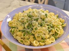 a blue bowl filled with pasta and peas on top of a checkered table cloth