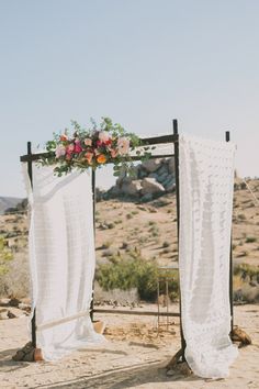 the wedding arch is decorated with white crochet fabric and pink flowers on it