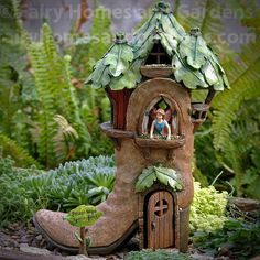 a fairy house with plants and rocks around it