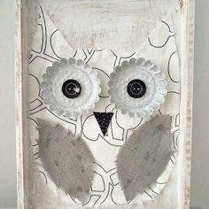 an owl made out of fabric and buttons on a white frame with black dots around the eyes