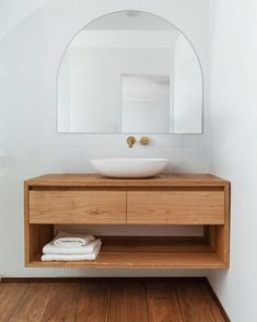 there is a sink and mirror in the bathroom with wood flooring on the side