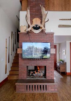 a deer head mounted to the side of a brick fireplace in a living room with hardwood floors