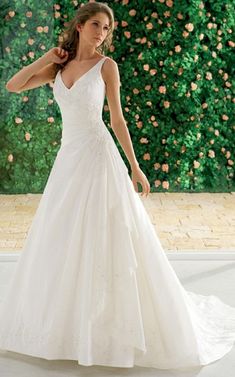 a woman in a white wedding dress posing for the camera with her hand on her hip