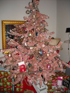 a pink christmas tree with presents under it