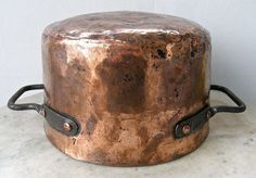 an old metal pot sitting on top of a white counter next to a black handle