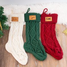 three pairs of knitted christmas stockings sitting on top of a wooden floor