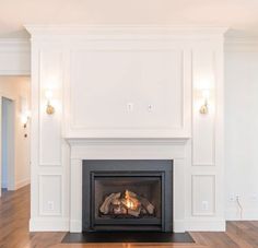 an empty room with a fire place in the center and wood floors on both sides