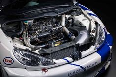 the engine compartment of a white car with blue stripes on it's front end