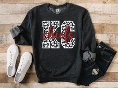 a black sweatshirt with the number 90 and leopard print on it next to some jeans