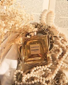 a chanel bottle surrounded by pearls and flowers