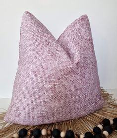 a pink pillow sitting on top of a table next to some black and white beads