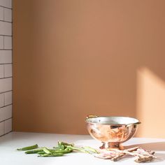 a silver bowl sitting on top of a counter next to green beans and other items