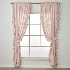 a window with pink ruffled curtains in front of a white wall and wooden floor