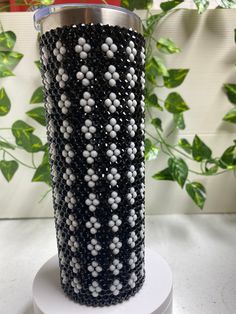 a black and white vase sitting on top of a table next to a green plant