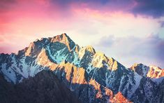 the mountains are covered in snow at sunset