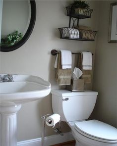 a white toilet sitting next to a sink in a bathroom under a mirror with shelves above it