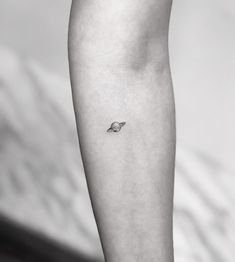 a black and white photo of a person's arm with a tiny bird on it