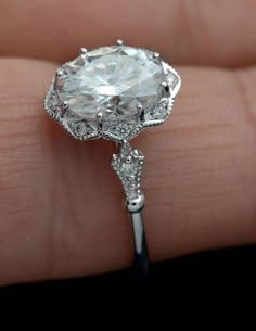 a woman's hand holding an engagement ring with a large diamond in the center