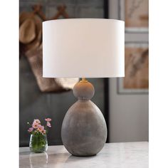 a table lamp sitting on top of a counter next to a vase with flowers in it