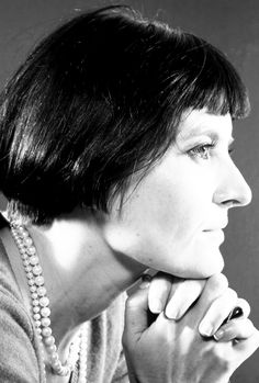 a black and white photo of a woman with her hand on her chin looking off to the side