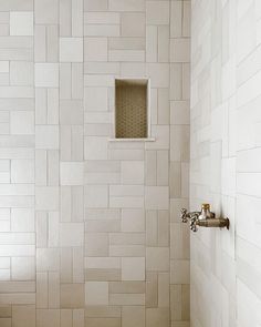 a white tiled bathroom with a small window