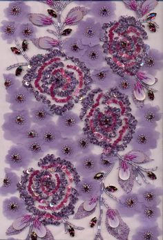 purple and pink flowers are arranged on a white background with silver beads in the center