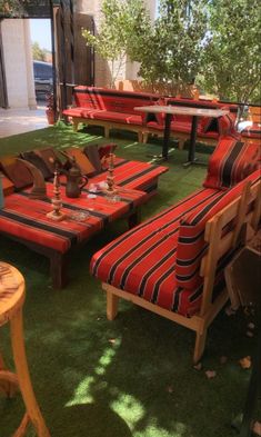 an outdoor seating area with red and black striped seats, tables and chairs on green grass