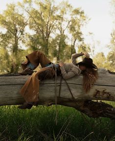 a woman laying on top of a log in the grass