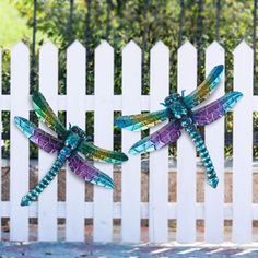 two colorful dragon sculptures sitting on top of a white fence