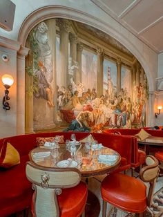 a dining area with red booths and tables in front of a painting on the wall