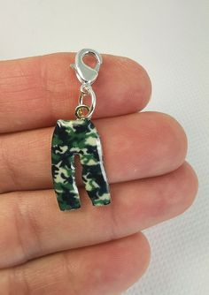 a hand holding a green and white tie dye charm with a small dog on it